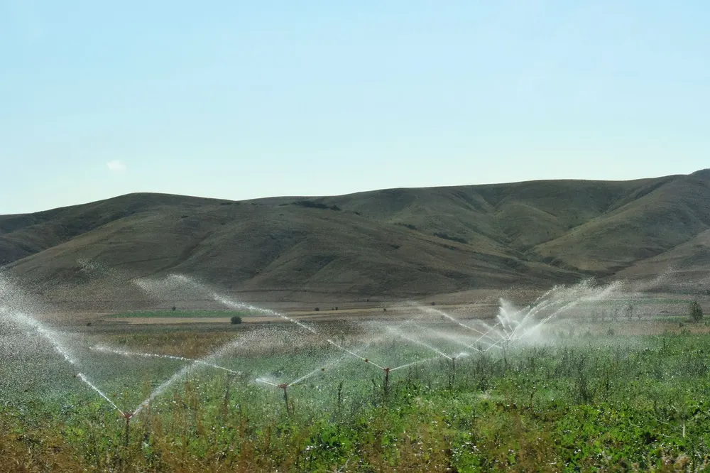 Sprinklers watering green farmland below the hills